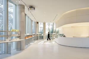 A modern interior space with a curved design, featuring people walking around, including one person in a suit, in a stylish and modern atmosphere