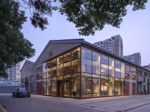A modern office space with a mix of glass and wood elements, featuring several chairs and a functional interior design