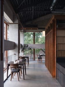 Modern restaurant interior with a large dining area, potted plants, and warm lighting