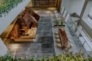 Open modern living area with a combined kitchen and dining space, tile flooring, chairs, a dining table, and a couch in the background, featuring a clean and minimalistic design with bright lighting