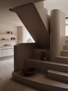 A house interior with two sets of concrete stairs, one on each side, and a decorative bowl near the bottom stairs