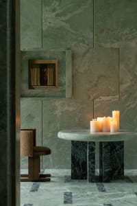 Cozy dining space with a green marble finish, a dining table, and three candles, set in a modern living area
