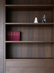 A wooden bookshelf filled with books in a cozy living area, creating a warm and inviting atmosphere for reading or studying
