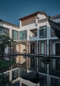 A sleek and elegant modern building with multiple windows, doors, and balconies, featuring a predominantly white exterior