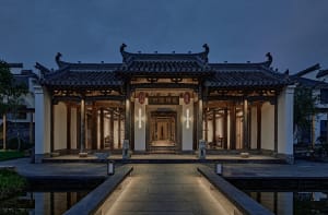 A stone building with intricate details and decorative elements, surrounded by a courtyard with lanterns and statues, conveying a sense of history and craftsmanship