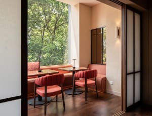 Warm and inviting dining space with wooden floors and walls, featuring a dining table, chairs, and a couch, with natural light from a window