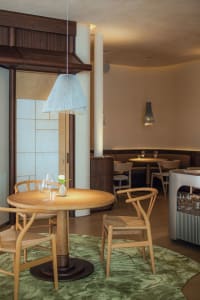 Warm and inviting restaurant interior with wooden floors, tables, and chairs, featuring wine glasses and a comfortable dining area
