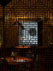 A warm and inviting Asian restaurant interior with wooden chairs, dining tables, and decorative vases, creating a cozy atmosphere