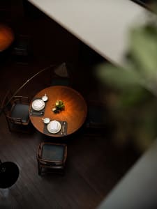 A warm and inviting dining area with a large wooden table surrounded by chairs, vases, and various tableware