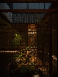 A serene Asian-style courtyard with a rock garden, potted plants, and a blend of traditional and modern architectural elements