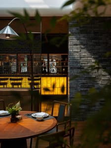 Cozy restaurant dining area with wooden tables, chairs, and bottles, set in a warm and inviting atmosphere