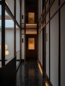 A hallway with wooden doors and walls adorned with oriental artwork, featuring a balcony and decorative elements