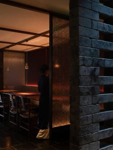 Cozy Asian restaurant dining area with a brick wall, a large dining table, and several chairs in a warm and inviting atmosphere