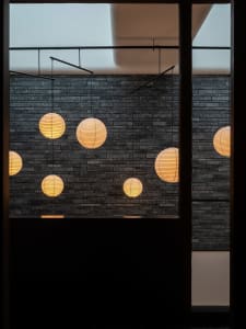 Modern interior design featuring a black brick wall with several lights hanging from it, creating a stylish and modern atmosphere