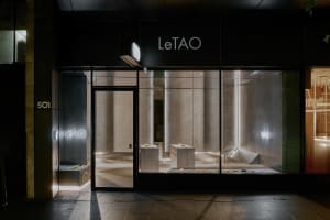 Empty storefront with a display window, wooden tables, and a sign reading Le Tao, set in a modern and stylish interior