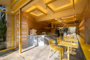 Warm and inviting restaurant interior with yellow walls, a counter, tables, chairs, and a dining area