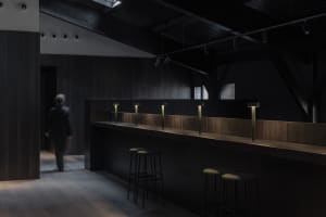 A modern bar area with a well-lit countertop and stools, creating a welcoming atmosphere