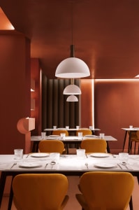 Warm and inviting dining space with a long table, yellow chairs, and soft lighting, surrounded by wood elements