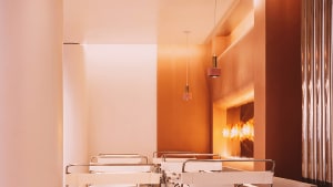 Empty classroom with white tables and pink walls, creating a calm and inviting atmosphere