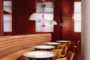 Cozy restaurant interior with red walls, wooden floors, and modern dining area with tables and chairs