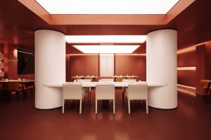 A modern dining area with a long wooden table and white chairs, surrounded by a red accent wall in a clean and neutral space