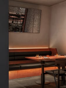 Warm and inviting restaurant interior with wooden tables, chairs, and benches, featuring wine glasses and a comfortable ambiance