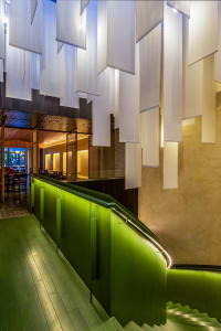Inviting restaurant interior with a green staircase, chairs, and a relaxed atmosphere