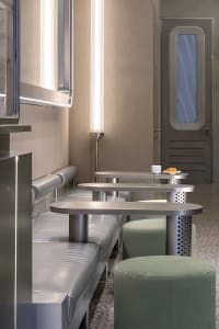 Inviting dining space with wooden tables, chairs, and a cup on one table, surrounded by comfortable seating for a pleasant dining experience