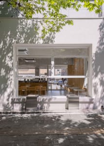 Inviting restaurant interior with large windows, dining tables, chairs, and a visible kitchen