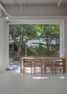 A bright indoor space with various chairs and a dining table, surrounded by natural light from a large window