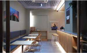 Empty restaurant interior with modern design, white walls, and dim lighting, featuring several tables and chairs in a spacious dining area