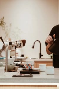 A casual kitchen with a focus on functionality, featuring a wood and metal construction, with appliances, cups, and utensils on the countertop