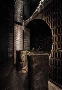 Bathroom with two sinks under a large mirror, stone countertop, and two bottles on the countertop