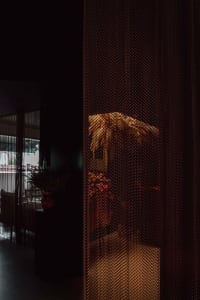 A cozy room with a floral patterned curtain, potted plants, and decorative vases, suggesting a living or dining space