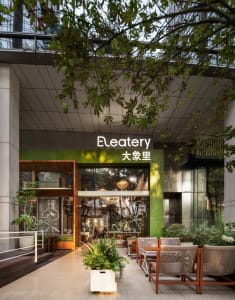 Modern dining space with multiple chairs and tables, potted plants, and a stylish atmosphere