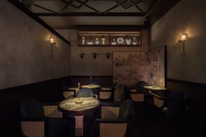 A cozy restaurant interior with multiple dining tables and chairs, wooden furniture, and a warm atmosphere