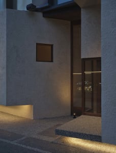 Exterior building facade with a doorway, two windows, and a window above the doorway, suggesting a sturdy concrete or similar material construction