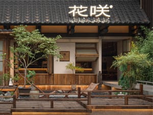 Asian restaurant with a wooden exterior, potted plants, a bar, and dining tables