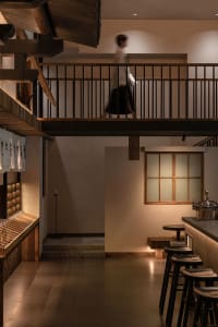 Dimly lit interior space with a staircase, chairs, and a cozy ambiance