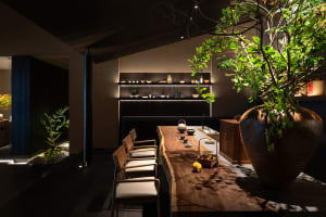 A cozy kitchen with a wooden dining table surrounded by chairs, featuring various items and a warm atmosphere