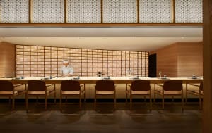 Cozy Asian restaurant interior with wooden floors and walls, featuring a sushi bar and traditional Japanese dining tables