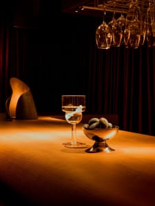 A well-lit dining area with a wooden table, wine glasses, bowls, and apples, creating a warm and inviting atmosphere