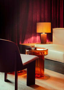 Cozy living area with a couch, chair, and table, featuring wooden furniture, lamps, and wine glasses
