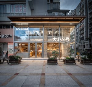A modern Asian restaurant with glass walls, dining tables, and potted plants, featuring a contemporary and minimalist interior