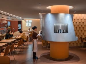 A modern Asian restaurant with a large dining area featuring tables, chairs, and Japanese writing on the walls, creating a warm and inviting atmosphere