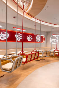 Dining area with multiple tables, benches, and red walls, creating an inviting atmosphere