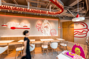 Casual restaurant interior with booths and tables, advertisements on the walls, and people dining and walking around