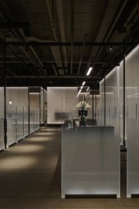 Empty modern retail space with glass walls, a black countertop, and two chairs, exuding minimalism and functionality