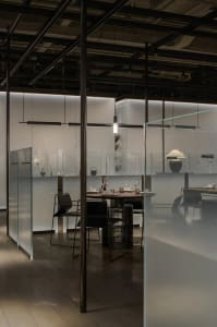 A modern restaurant interior with a dining table, chairs, and wine glasses, set up for dinner service in a clean and organized space