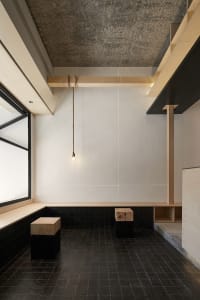 A modern dining space with two wooden tables and chairs, two benches, and white walls, giving a clean and bright appearance